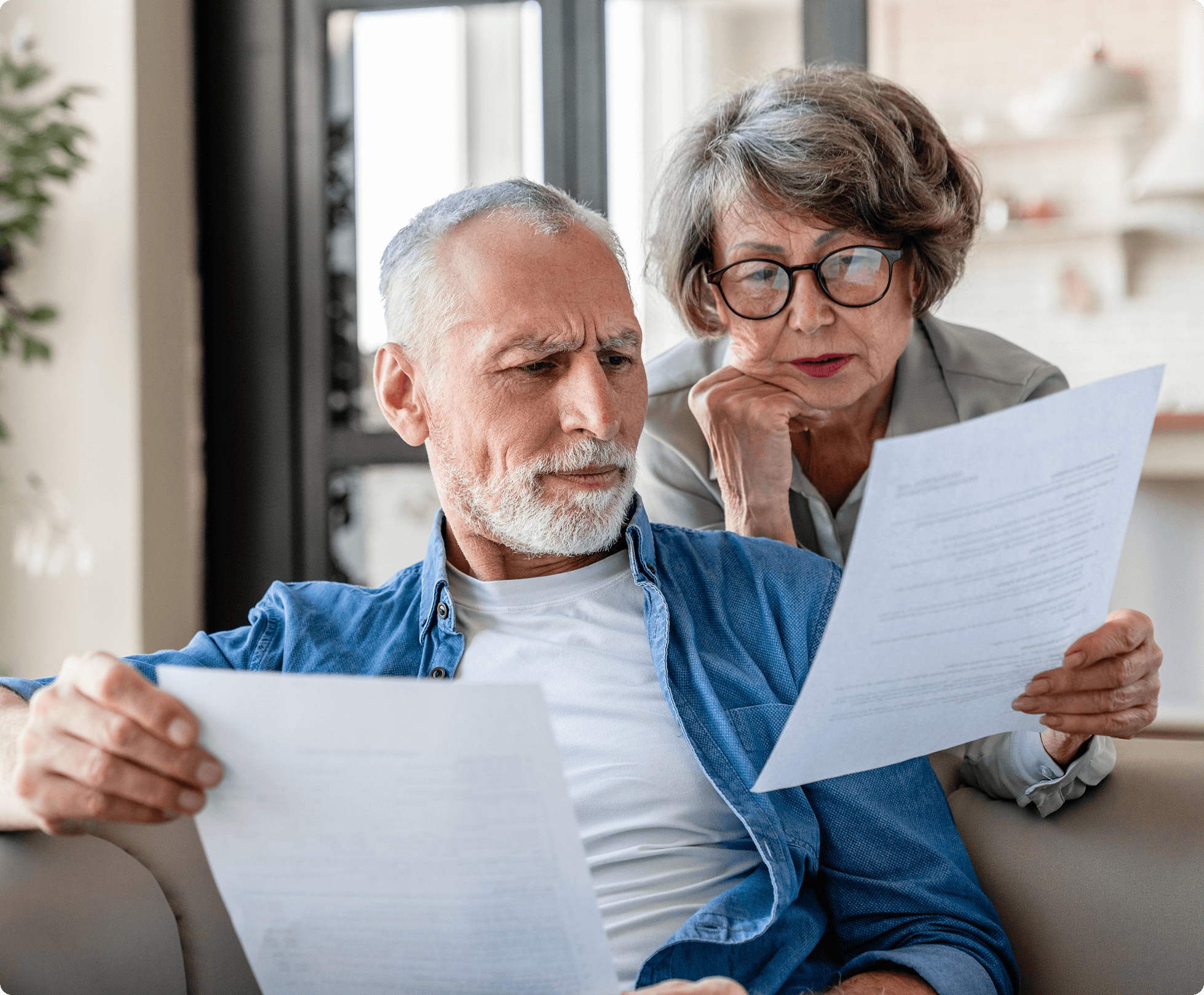 Elderly couple reading paperwork at home